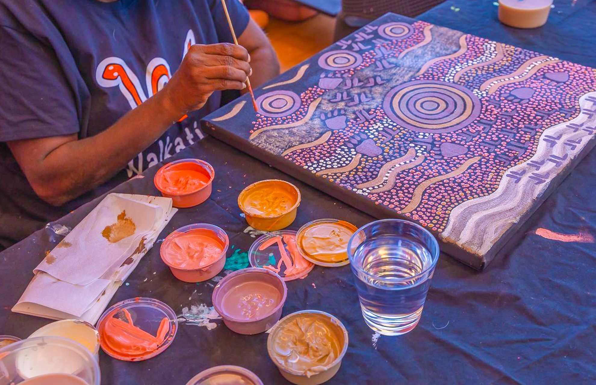 Central Australian Aboriginal artist working on a painting at the Gallery of Central Australia