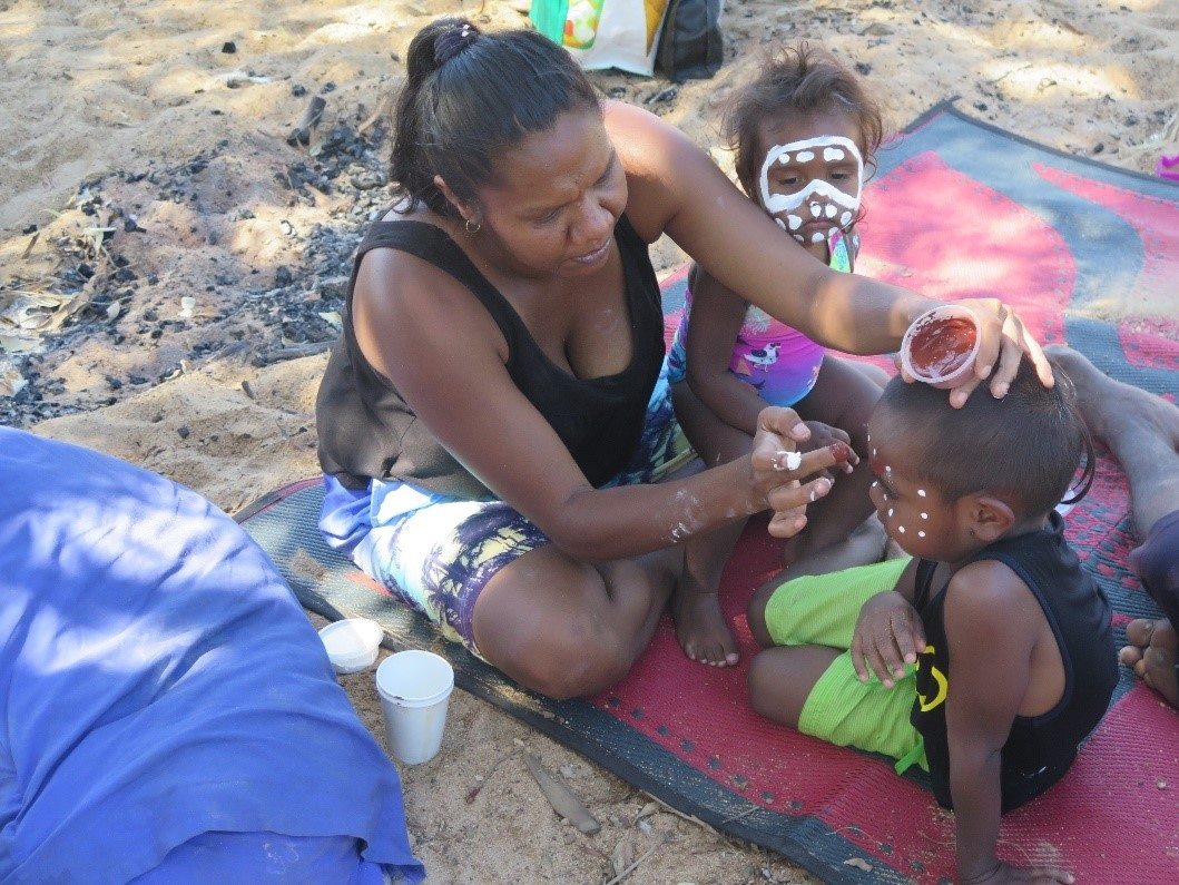 Aboriginal Elder applying traditional face paint to children