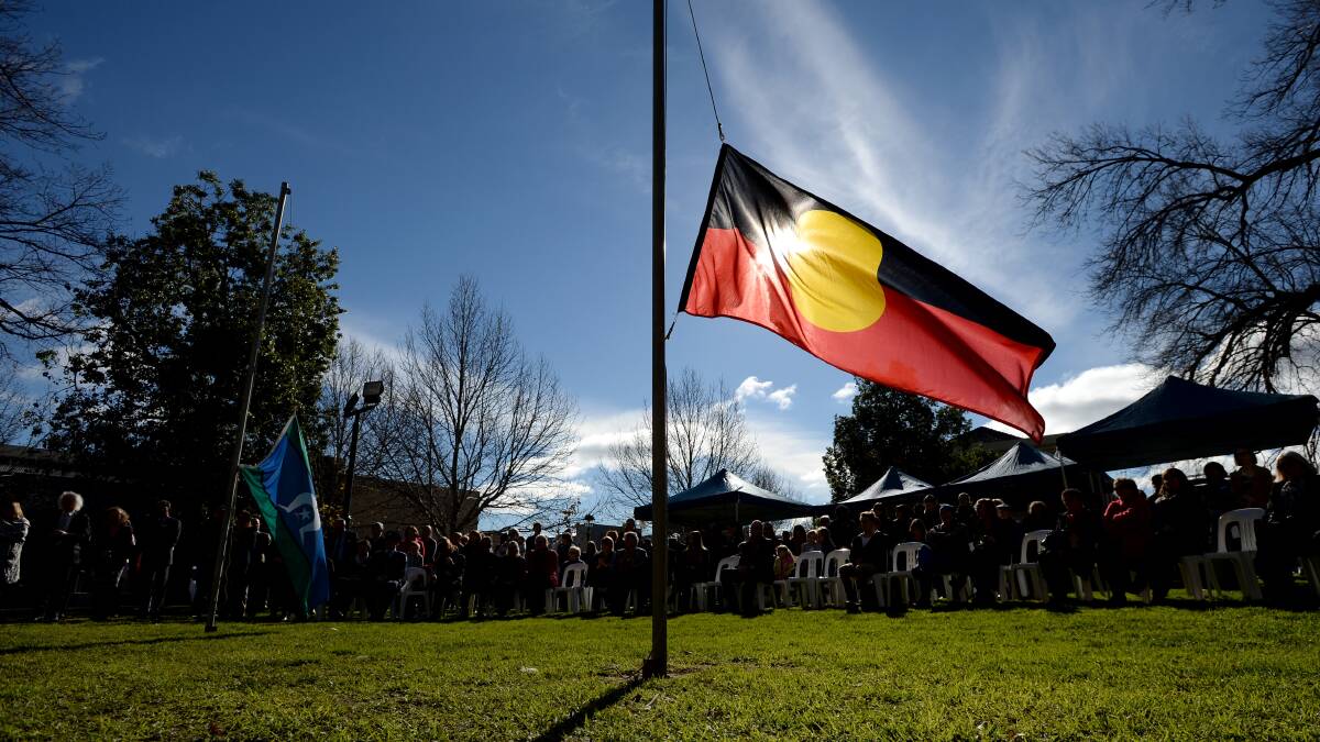 Community gathering at a NAIDOC Week event with flags and shared cultural activities