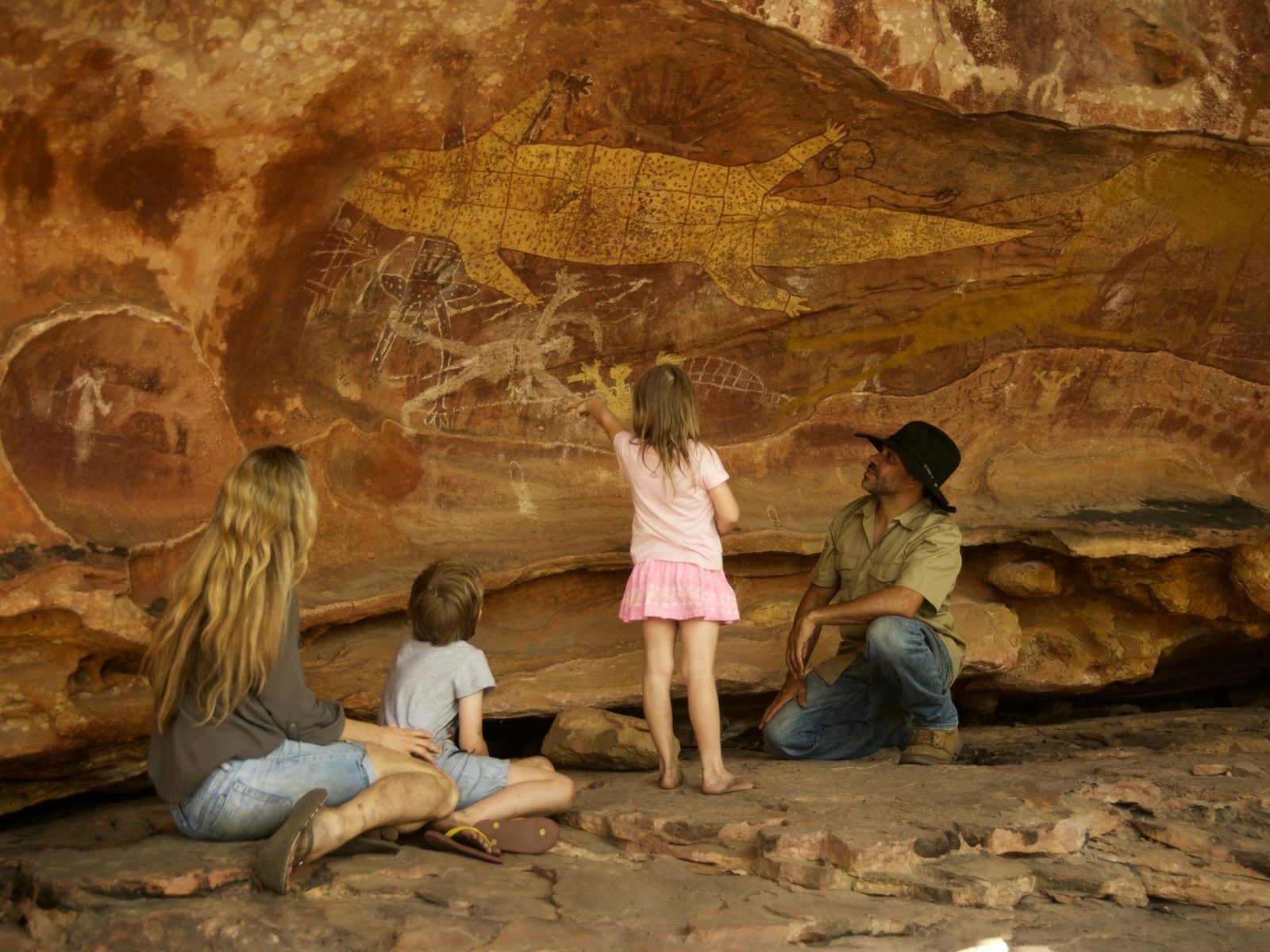 Sandstone rock art panel with ochre figures and stencils