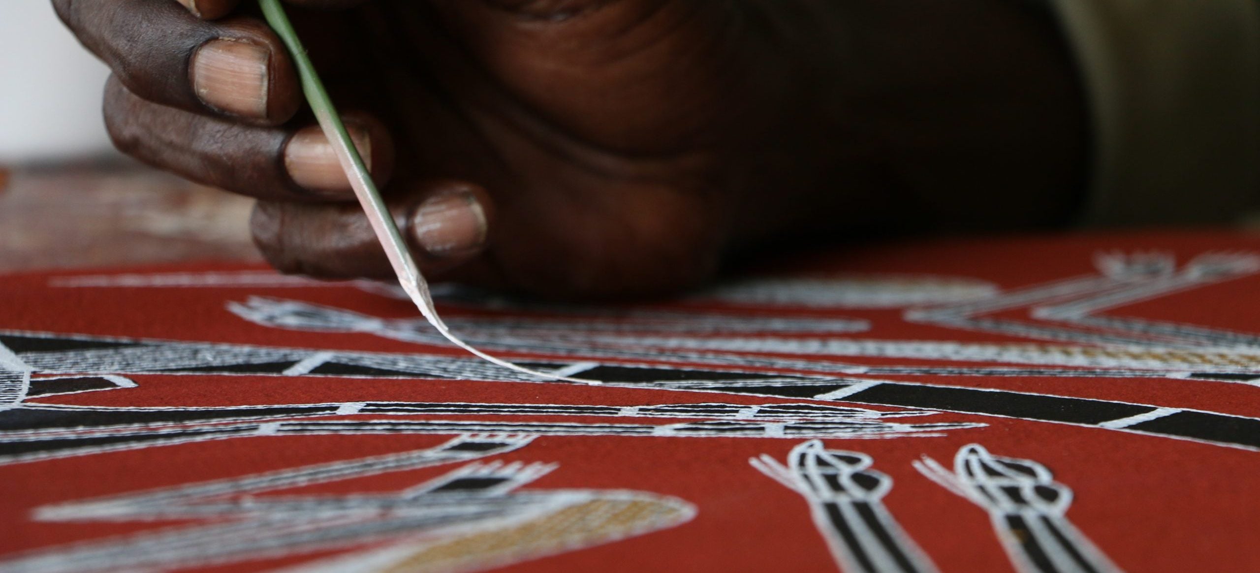 Aboriginal artists working on rarrk crosshatching paintings showing the detailed line technique