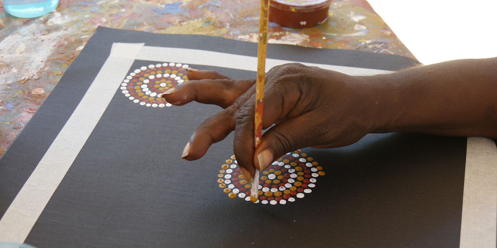 An Aboriginal artist working on a dot painting